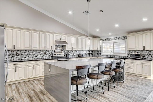 kitchen featuring stainless steel appliances, a center island, a breakfast bar area, and decorative light fixtures