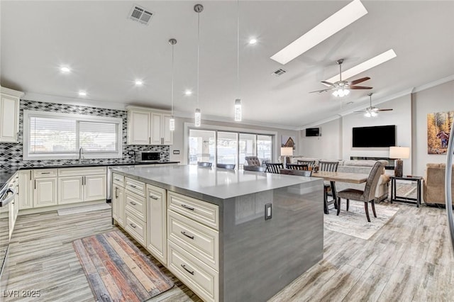 kitchen with a kitchen island, sink, hanging light fixtures, and backsplash