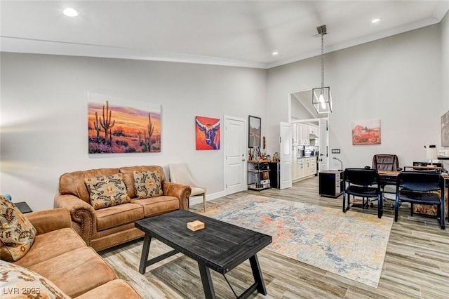 living room featuring ornamental molding, light hardwood / wood-style flooring, and a high ceiling