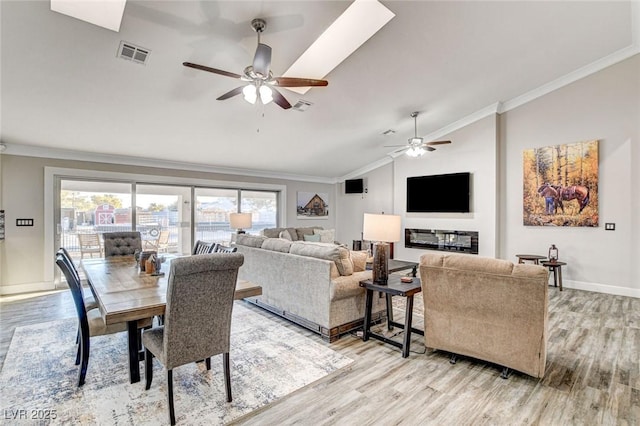 living room with crown molding, vaulted ceiling, and light wood-type flooring