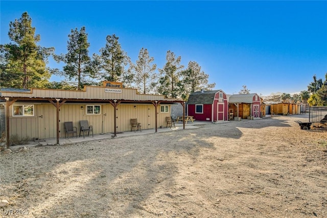 rear view of property featuring a patio and a shed