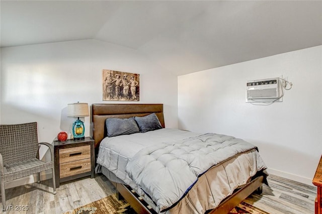 bedroom with lofted ceiling, light hardwood / wood-style floors, and a wall mounted AC