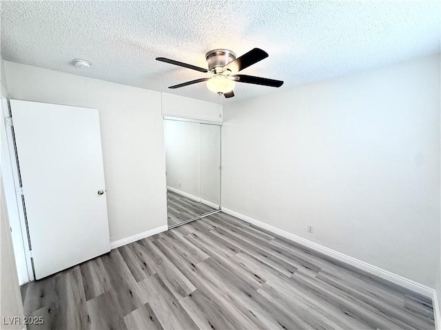 unfurnished bedroom featuring a closet, ceiling fan, a textured ceiling, and light hardwood / wood-style flooring