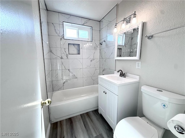 full bathroom featuring hardwood / wood-style flooring, tiled shower / bath combo, vanity, a textured ceiling, and toilet