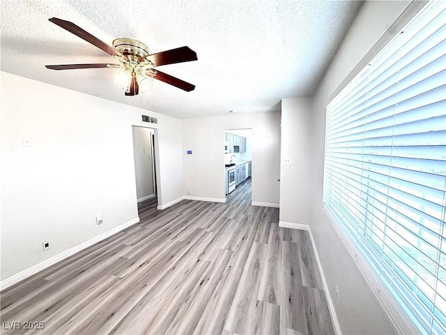 unfurnished living room with ceiling fan, a textured ceiling, and light wood-type flooring