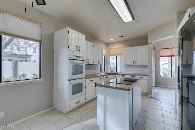 kitchen with white cabinetry, a kitchen island, and white double oven