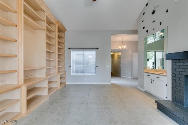 unfurnished living room featuring an inviting chandelier and a brick fireplace