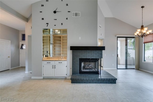 unfurnished living room with light tile patterned flooring, high vaulted ceiling, a fireplace, sink, and an inviting chandelier