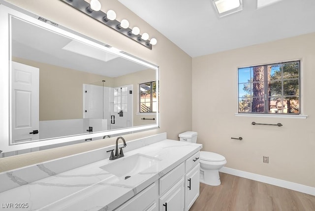 bathroom with a walk in shower, toilet, wood finished floors, vanity, and baseboards