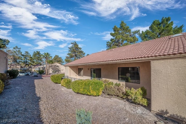 exterior space featuring a tiled roof and stucco siding