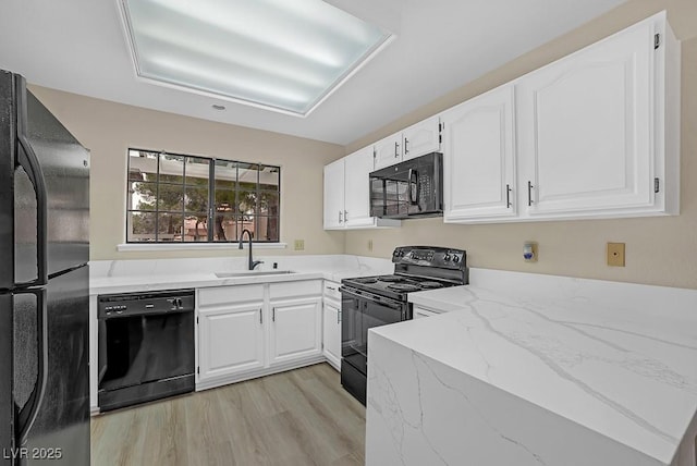 kitchen with black appliances, a sink, white cabinetry, and light stone countertops