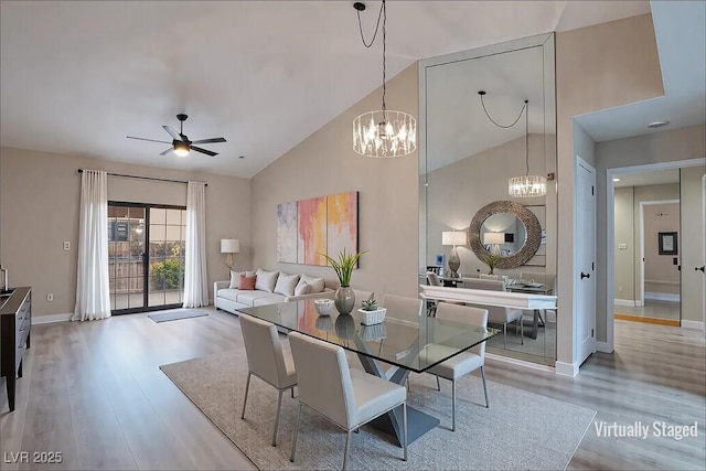 dining room featuring high vaulted ceiling, ceiling fan with notable chandelier, baseboards, and wood finished floors