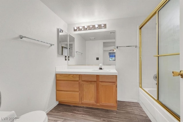 full bathroom with enclosed tub / shower combo, hardwood / wood-style floors, vanity, and toilet