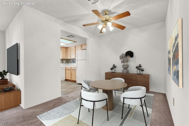 carpeted dining area with ceiling fan and a textured ceiling