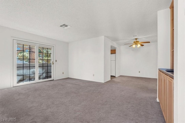 unfurnished living room with carpet, a textured ceiling, and ceiling fan