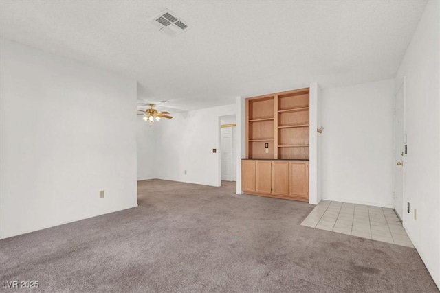 unfurnished room with ceiling fan, light carpet, and a textured ceiling