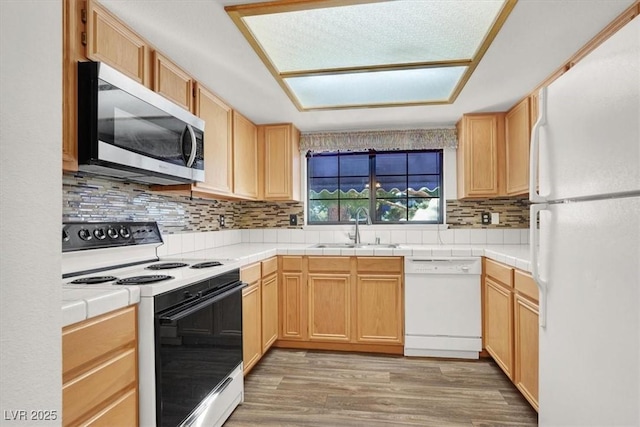 kitchen with tile countertops, tasteful backsplash, sink, hardwood / wood-style flooring, and white appliances