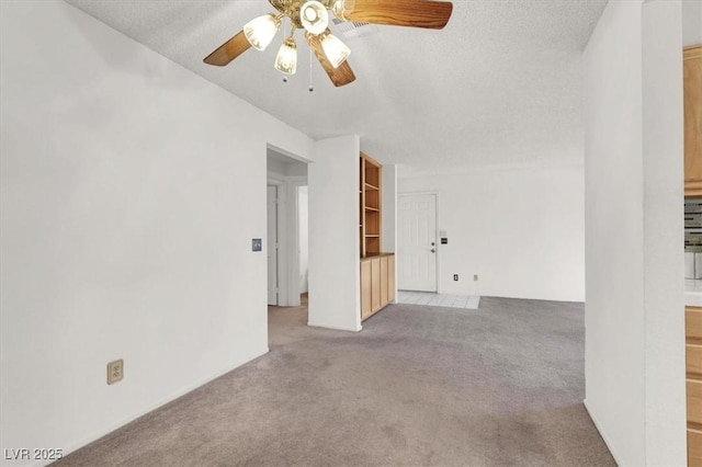 unfurnished room with ceiling fan, light colored carpet, and a textured ceiling