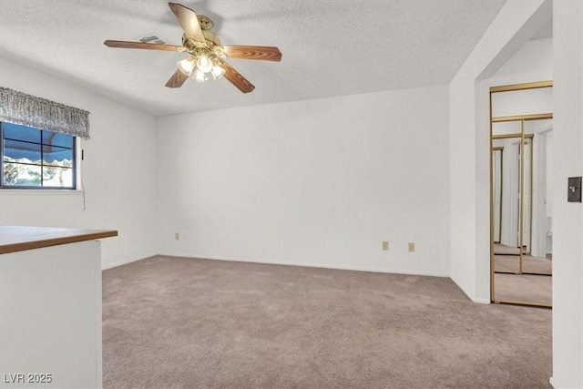 spare room with ceiling fan, light carpet, and a textured ceiling