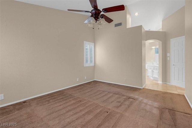 carpeted empty room with ceiling fan and high vaulted ceiling