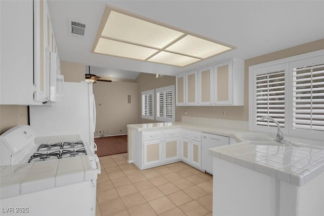 kitchen with tile countertops, sink, white cabinets, kitchen peninsula, and white appliances