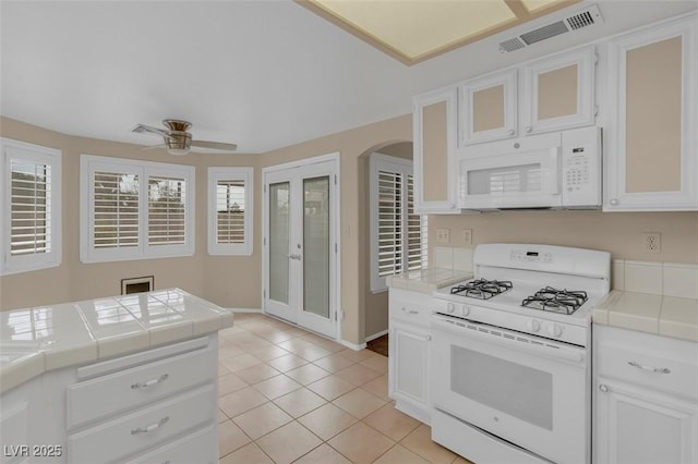 kitchen featuring light tile patterned flooring, white appliances, tile counters, and white cabinets