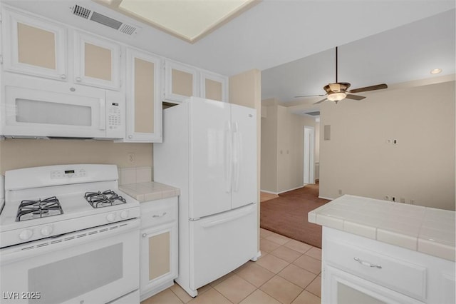 kitchen featuring white cabinetry, tile counters, white appliances, and light tile patterned floors