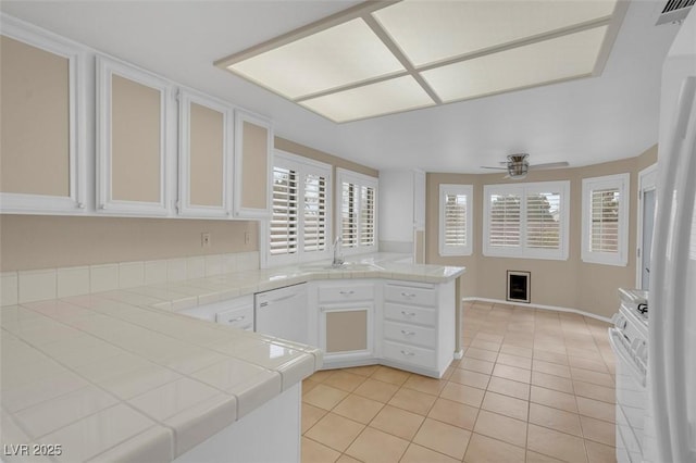 kitchen with white appliances, tile counters, kitchen peninsula, and white cabinets