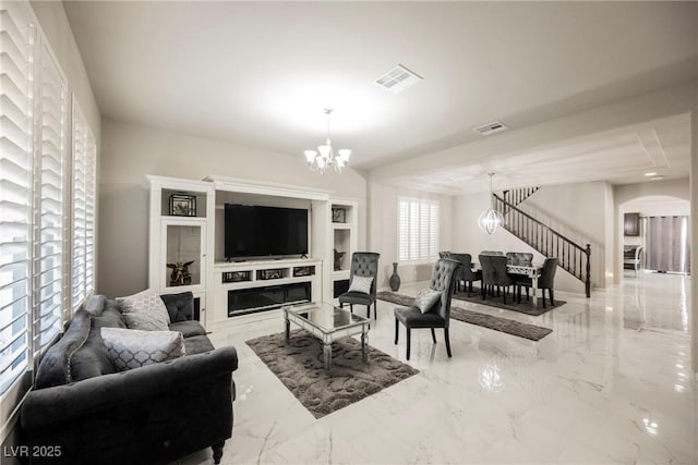 living room with a notable chandelier, a fireplace, and built in shelves