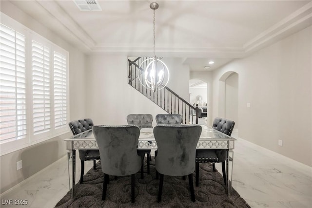 dining room with an inviting chandelier and a raised ceiling