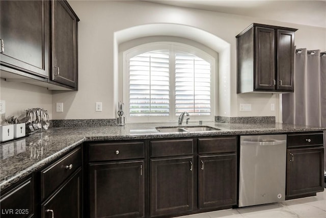 kitchen with stainless steel dishwasher, sink, dark brown cabinets, and dark stone countertops