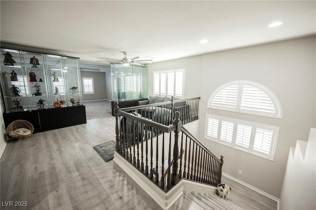 stairway with hardwood / wood-style flooring and ceiling fan