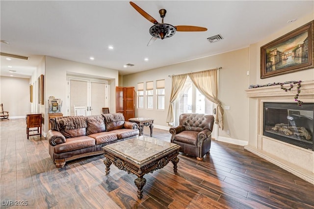 living room with ceiling fan, a premium fireplace, and dark hardwood / wood-style flooring