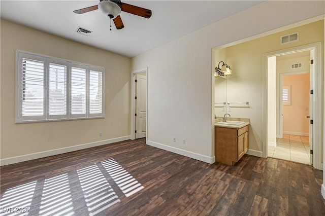 unfurnished bedroom featuring ceiling fan, dark hardwood / wood-style floors, and sink