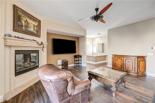 living room with ceiling fan, wood-type flooring, and a fireplace