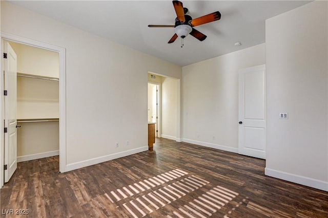 unfurnished bedroom featuring ceiling fan, a spacious closet, dark hardwood / wood-style flooring, and a closet