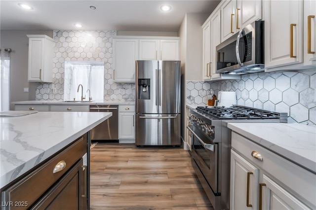 kitchen with light stone counters, sink, white cabinets, and appliances with stainless steel finishes