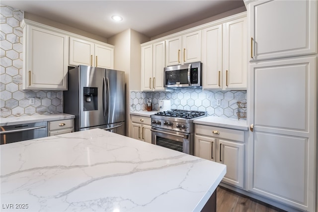 kitchen featuring light stone counters, backsplash, white cabinets, and appliances with stainless steel finishes