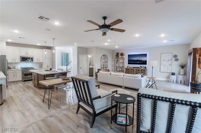 living room with light hardwood / wood-style flooring and ceiling fan