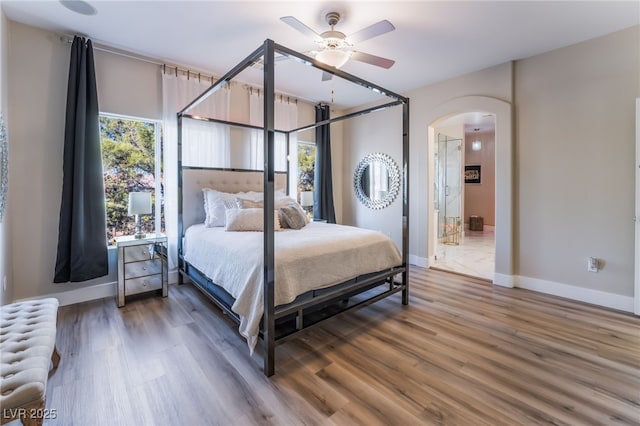 bedroom with wood-type flooring, radiator, ceiling fan, and ensuite bath