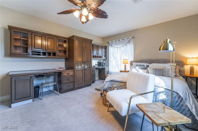 bedroom featuring built in desk, light colored carpet, and ceiling fan