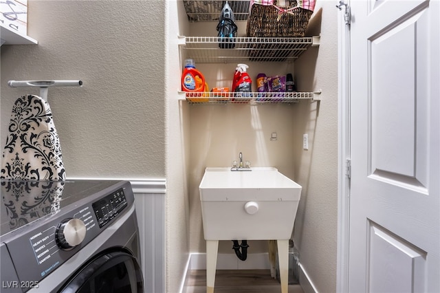 clothes washing area with wood-type flooring, washer / dryer, and sink