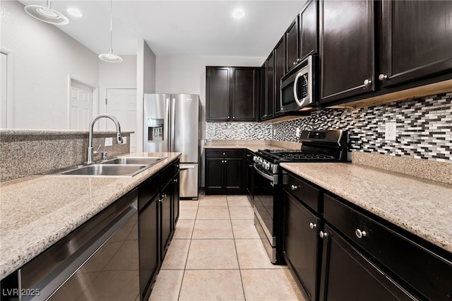 kitchen featuring sink, decorative light fixtures, light tile patterned floors, appliances with stainless steel finishes, and backsplash