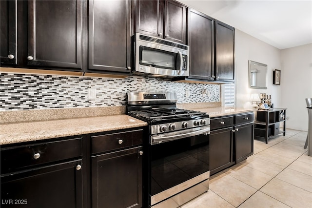 kitchen featuring stainless steel appliances, tasteful backsplash, light tile patterned floors, and dark brown cabinetry