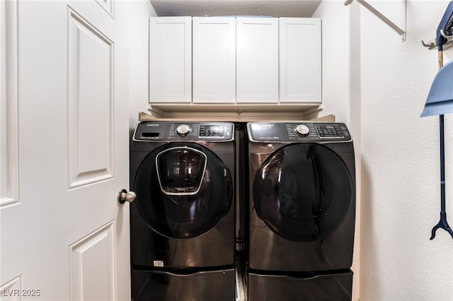 clothes washing area featuring cabinets and washer and clothes dryer