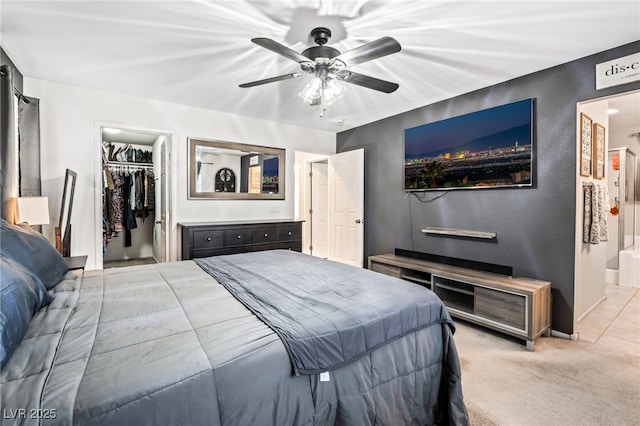 carpeted bedroom featuring ceiling fan, ensuite bathroom, a closet, and a walk in closet