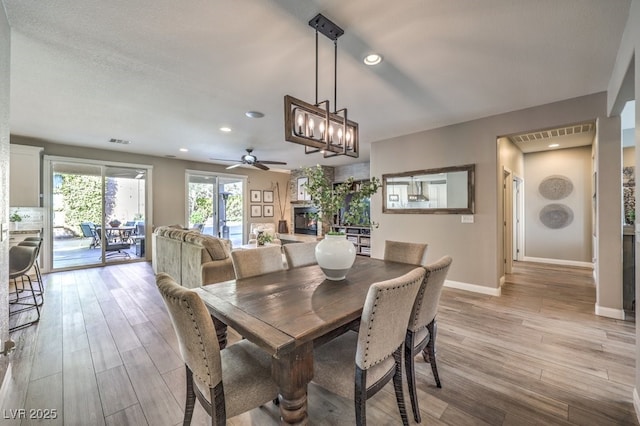 dining area with ceiling fan, a fireplace, and light hardwood / wood-style floors