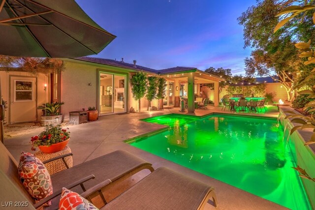 pool at dusk featuring a patio area