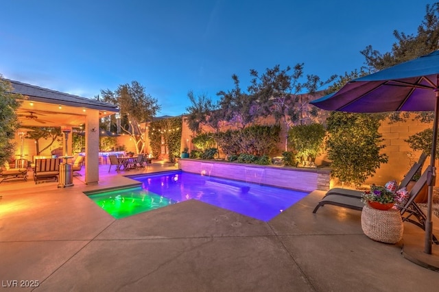 pool at dusk featuring an outdoor hangout area and a patio area