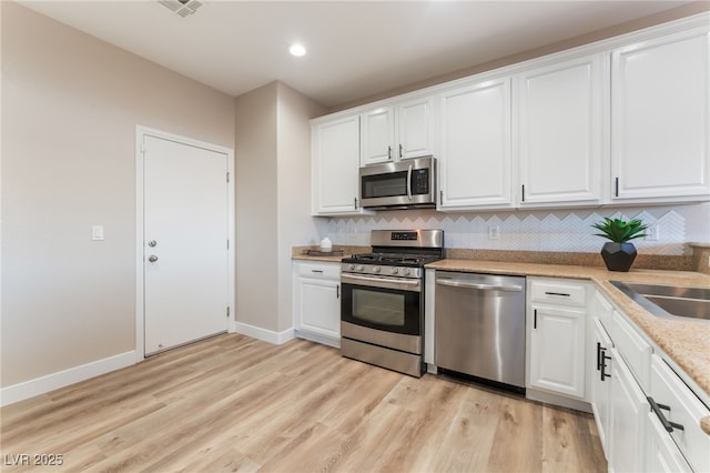 kitchen featuring white cabinetry, tasteful backsplash, stainless steel appliances, and light hardwood / wood-style floors